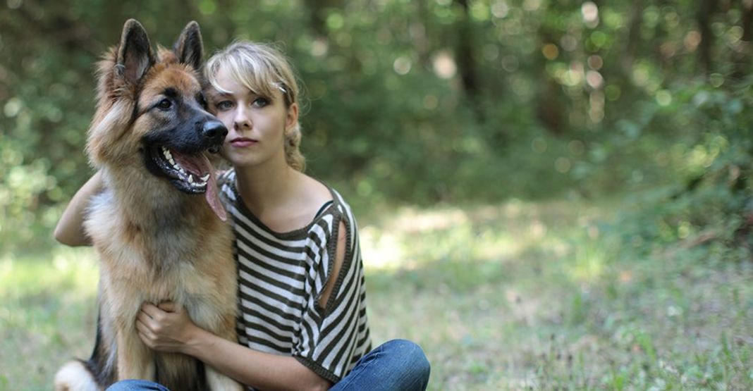 Une femme assise avec un chien dans une forêt 