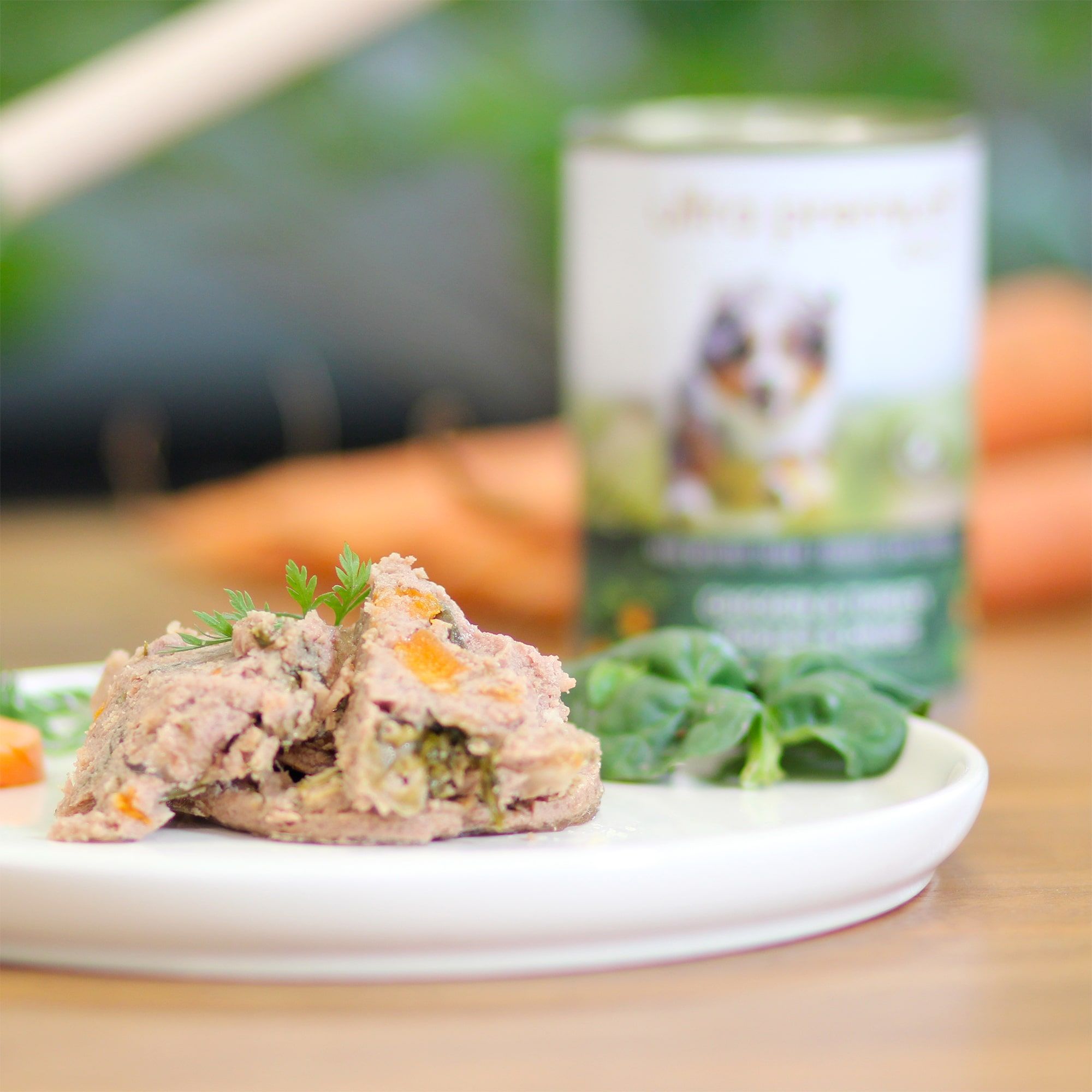 Boîte de pâtée pour chien sans céréales au poulet & dinde sur une planche en bois avec des rondelles de carotte au premier plan
