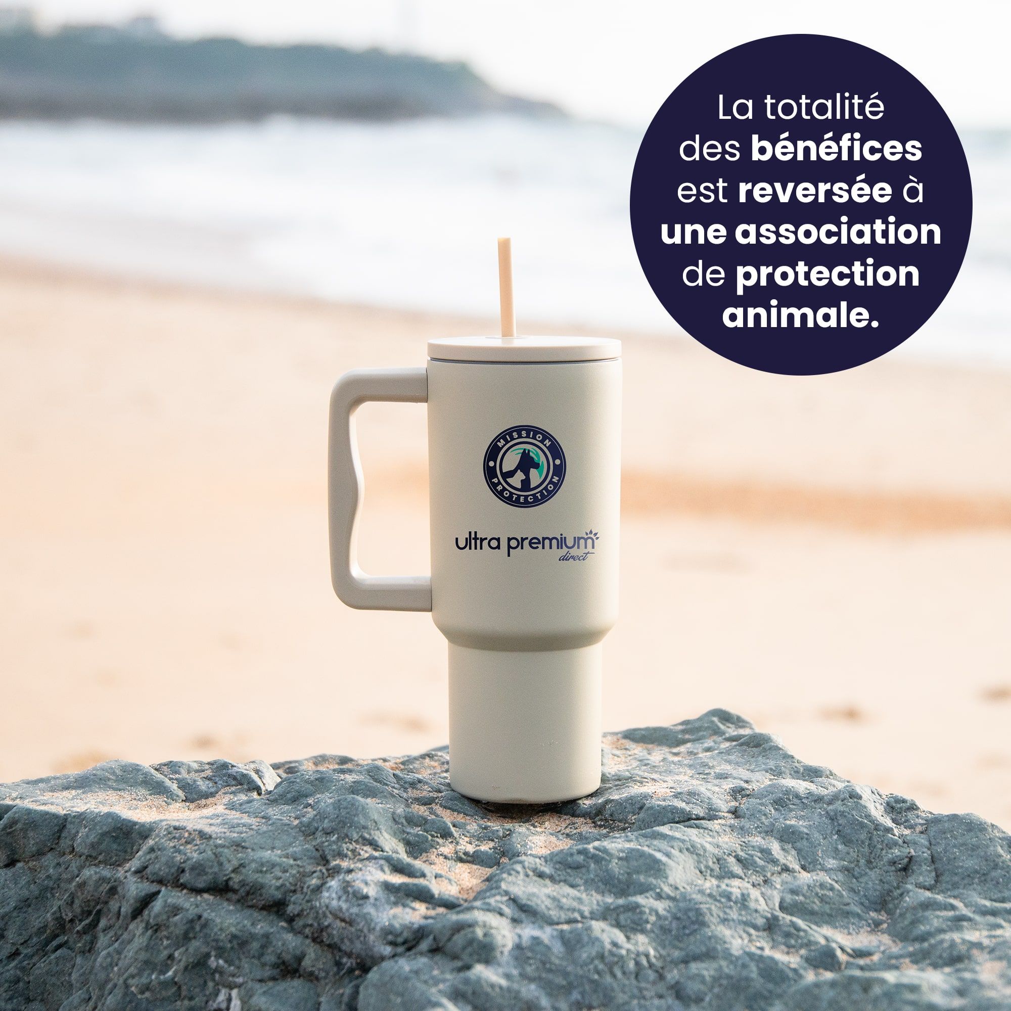 Mug réutilisable avec paille Mission protection Pays Basque  sur un rocher avec une plage en fond avec pastille qui indique qu'une partie des bénéfices sera reversée à une association de protection animale