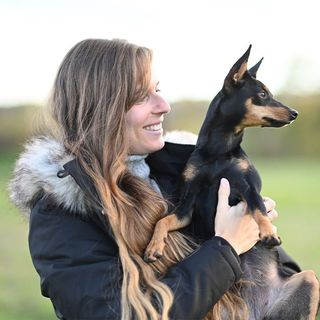 Une femme tenant un Pinscher 
