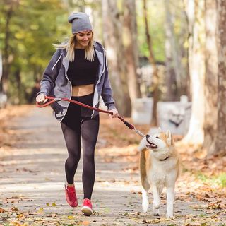 Une femme courant avec son chien dans un parc