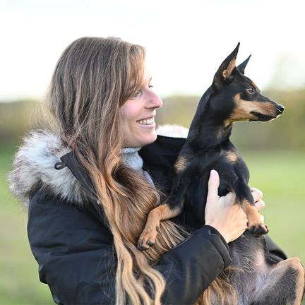 Une femme tenant un Pinscher 