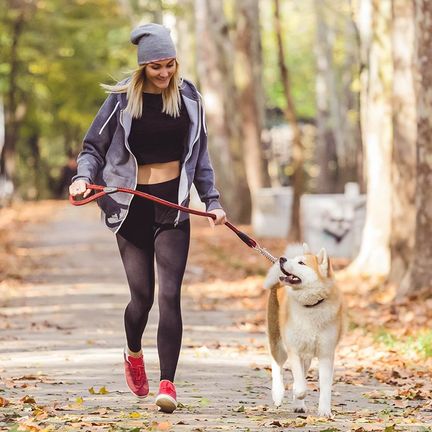 Une femme courant avec son chien dans un parc
