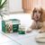 Zakje malse plakjes in saus voor honden - Lam en sperziebonen naast een Cocker Spaniel