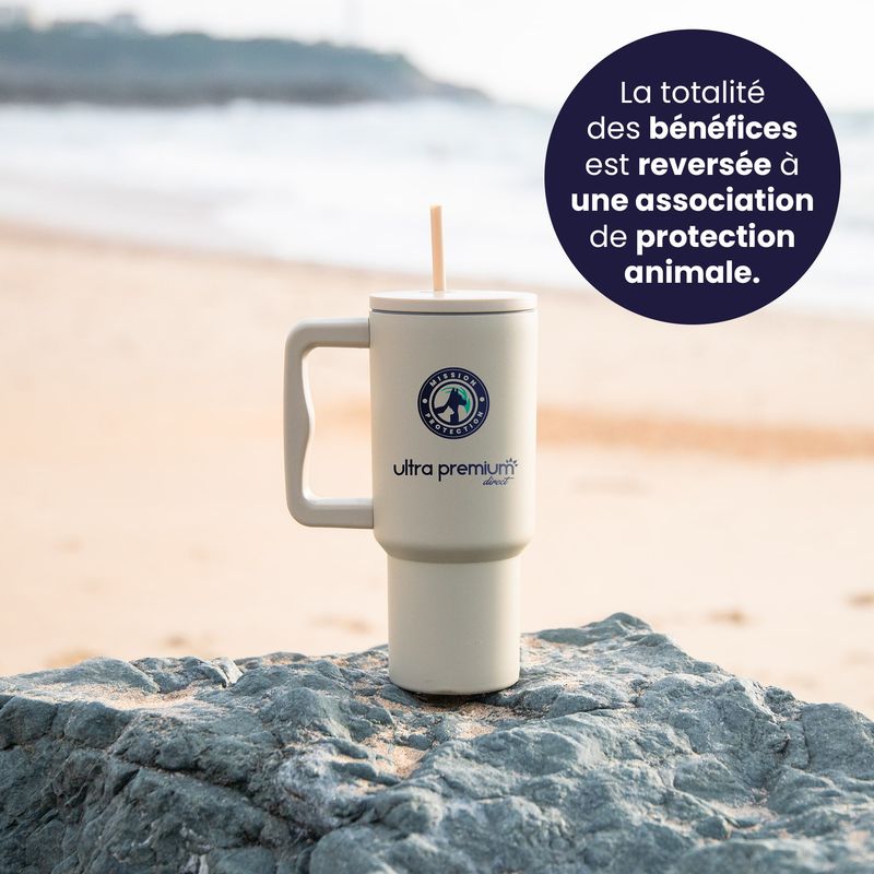 Mug réutilisable avec paille Mission protection Pays Basque  sur un rocher avec une plage en fond avec pastille qui indique qu'une partie des bénéfices sera reversée à une association de protection animale