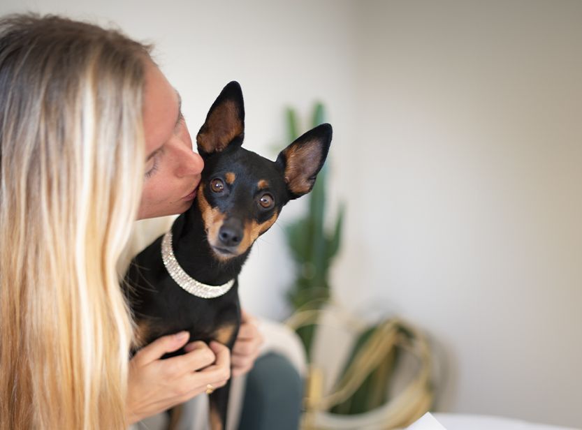 Lison qui fait un bisou à sa chienne Pixie, un pinscher nain.
